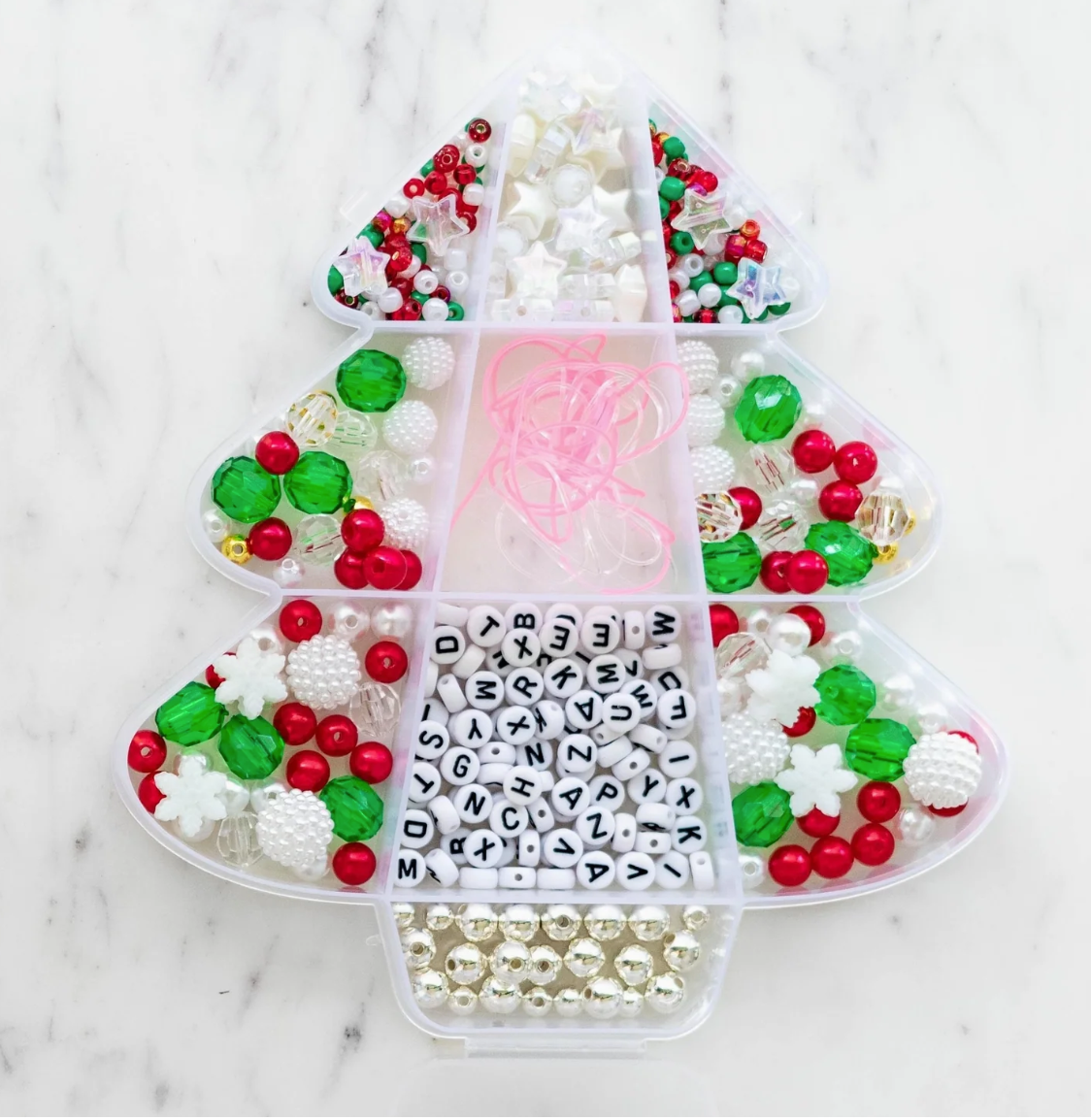 Assorted beads and letters in a heart-shaped organizer on a marble surface