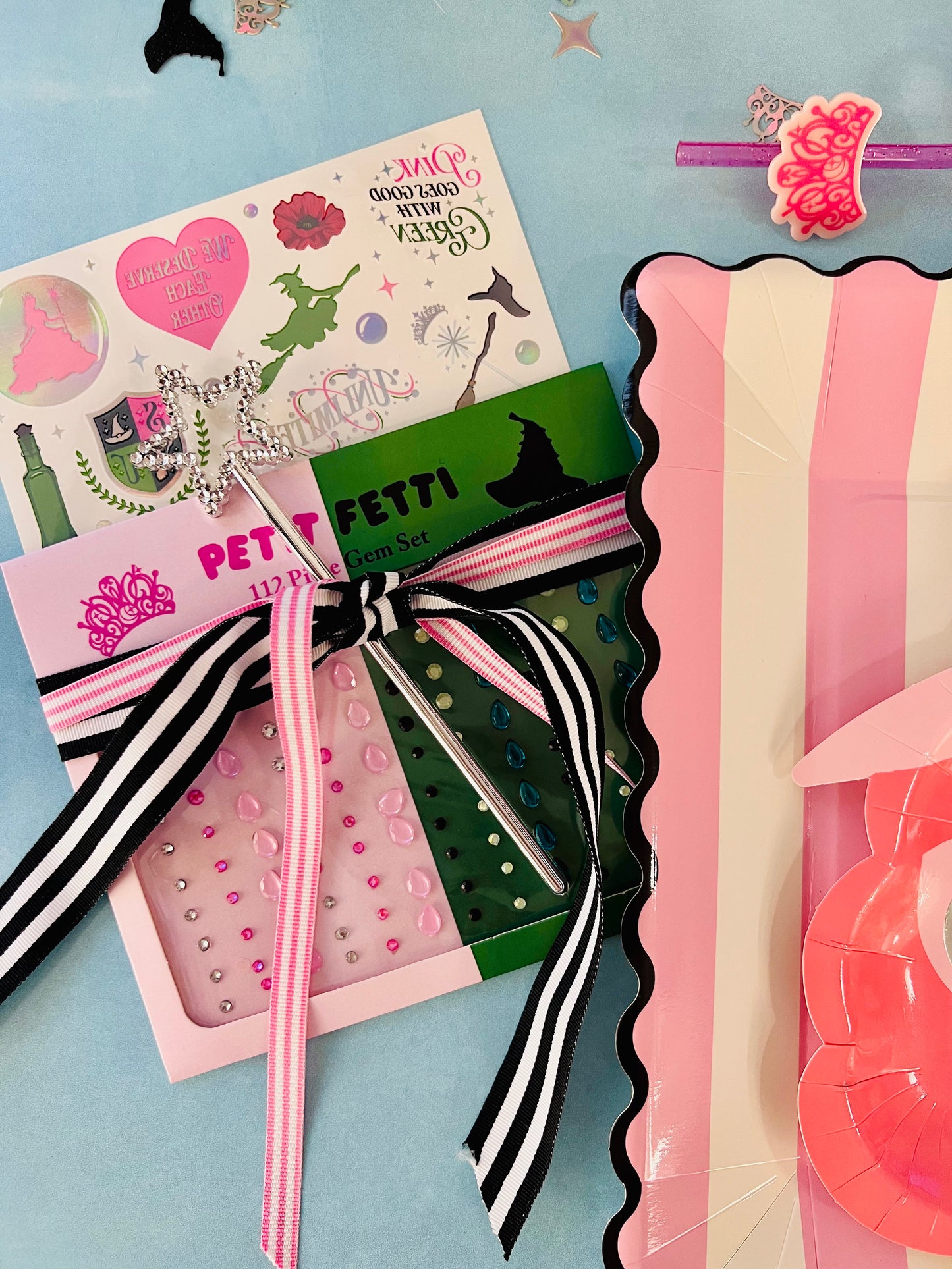 Collection of stationery items including a card, ribbons, and a pen set on a light blue background.