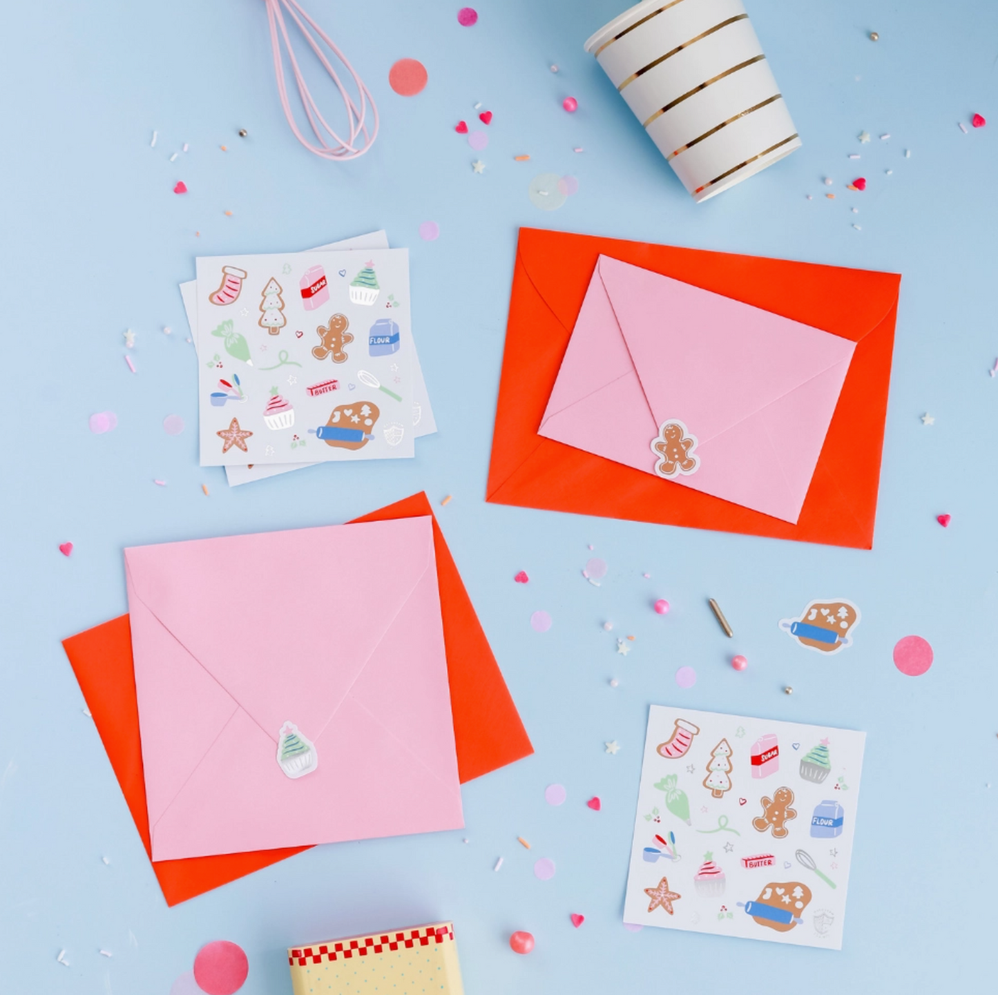 Colorful stationery items including envelopes and stickers on a blue background with confetti.