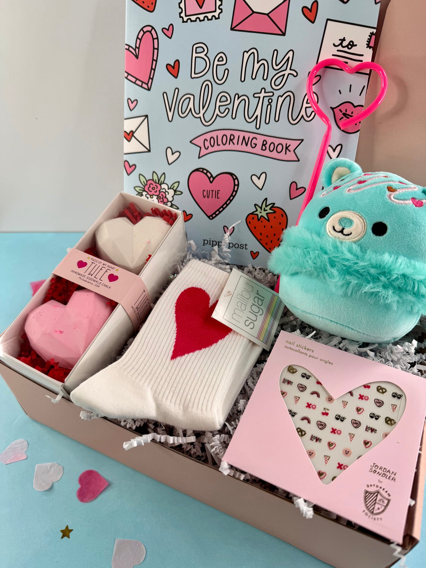 Valentine's Day themed gift box with heart-themed items on a light blue background