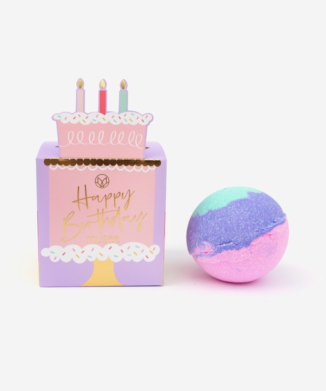 A purple birthday-themed box with a balloon and a cake design, alongside a multicolored (balloon-like) bath confetti ball.