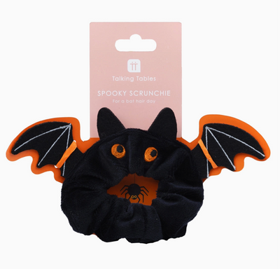 Black bat-shaped scrunchie with orange accents on a white background