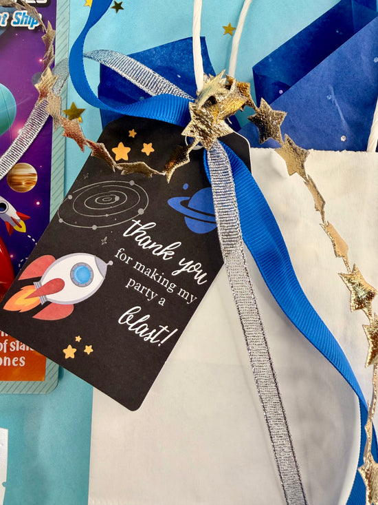 Space-themed party favor bag with a tag and decorative elements.