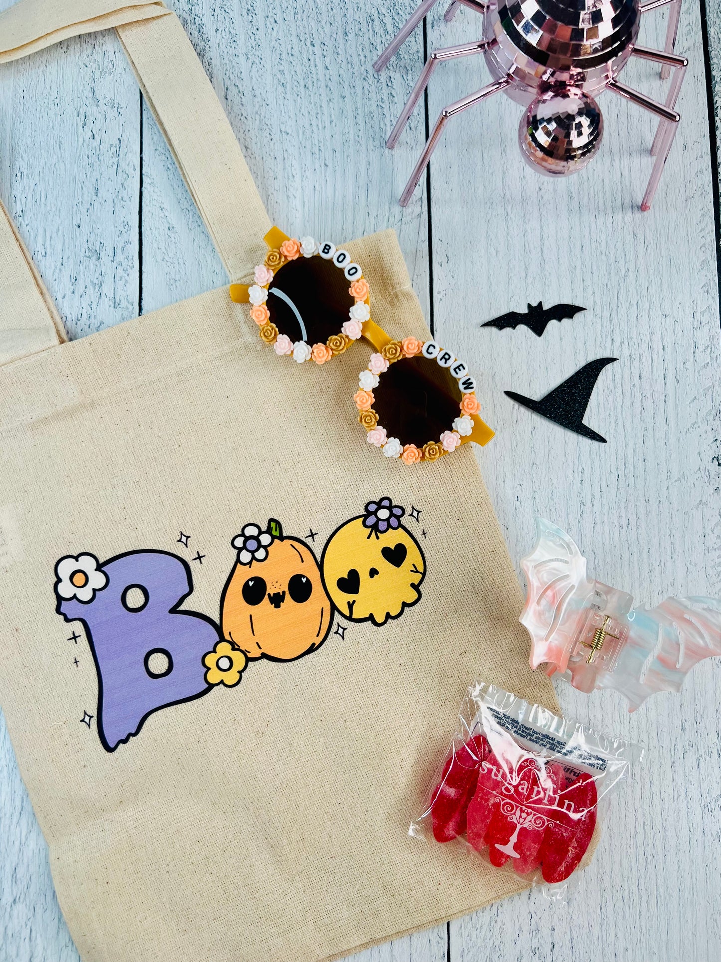 Halloween-themed tote bag with colorful pumpkins, candy, and decorative items on a wooden surface.
