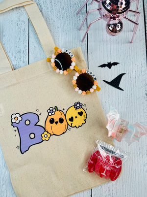 Halloween-themed tote bag with colorful pumpkins, candy, and decorative items on a wooden surface.