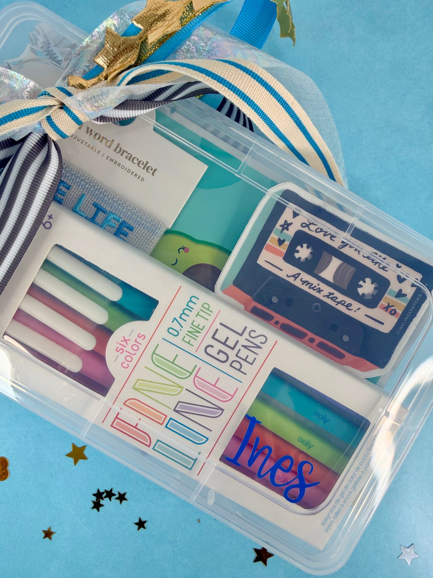 Set of colorful gel pens in a clear case with decorative elements on a blue background