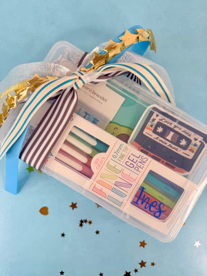 Set of pens in a clear case with decorative ribbons on a blue background