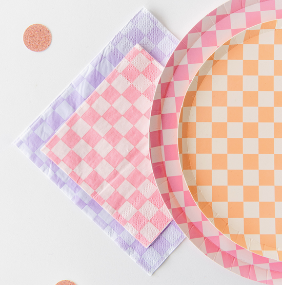 Checkered paper plates and napkins in pink, purple, and orange on a white background
