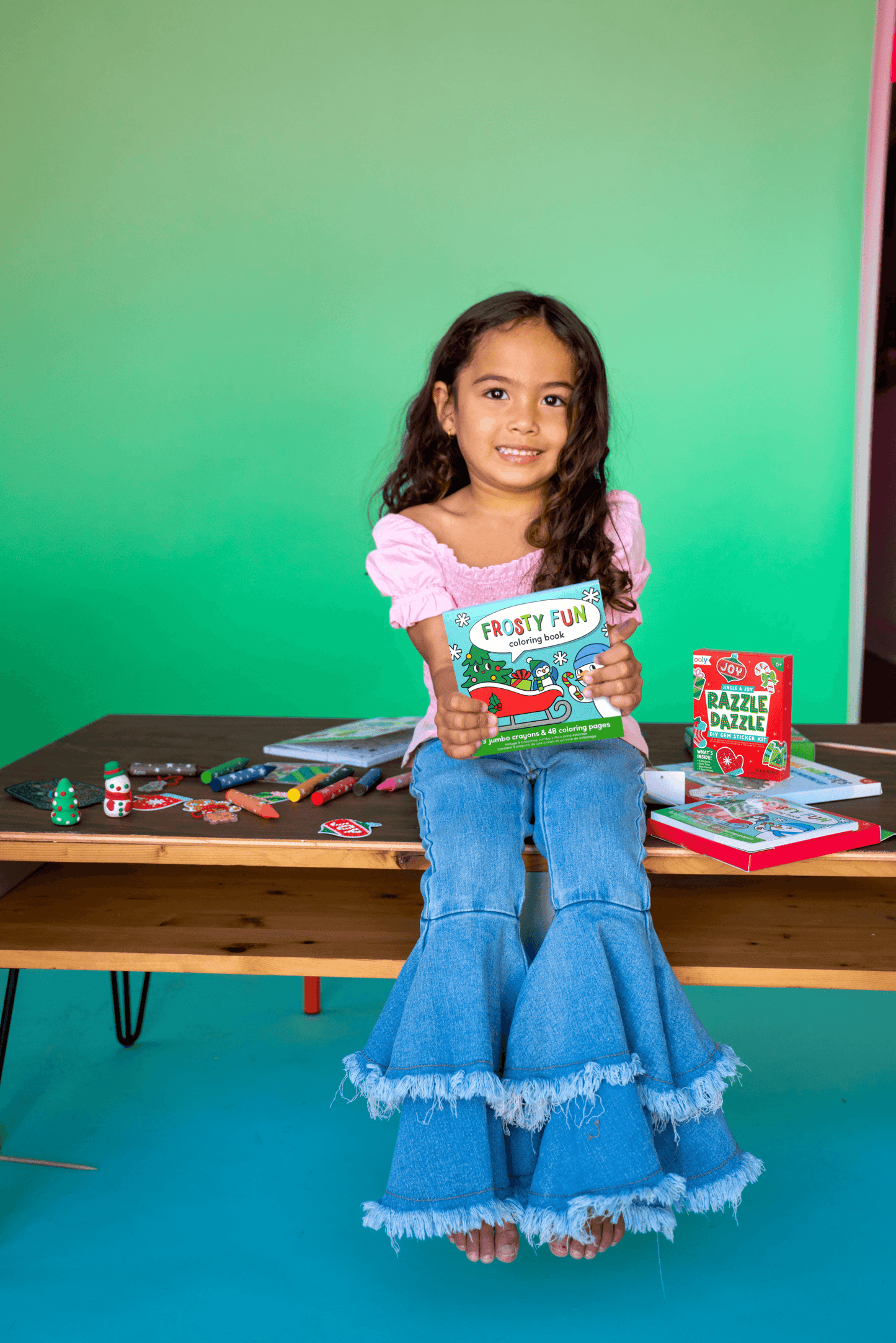 Young girl holding a book in a classroom setting with educational materials on a table.