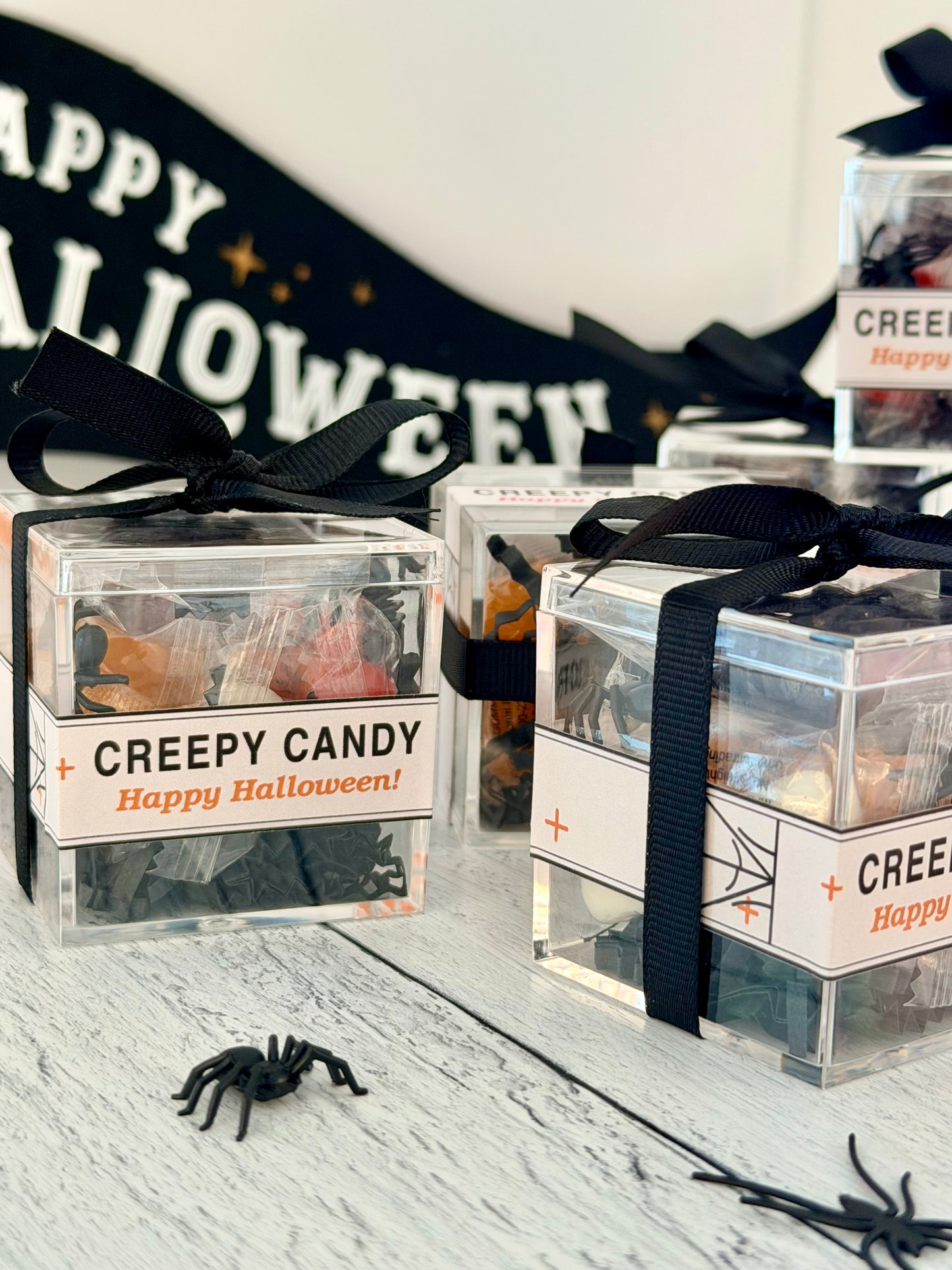 Clear Creepy Candy Halloween favor cubes with wrapped gummies, mini spiders, black ribbon and pink or orange labels