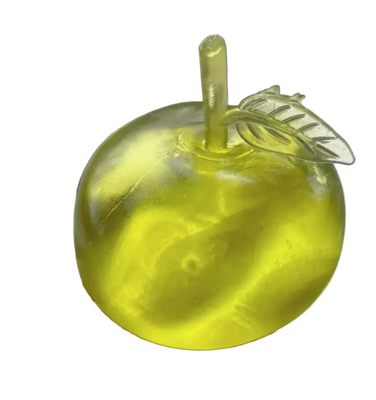 Clear plastic apple with a straw inside, held by a hand against a blurred background.