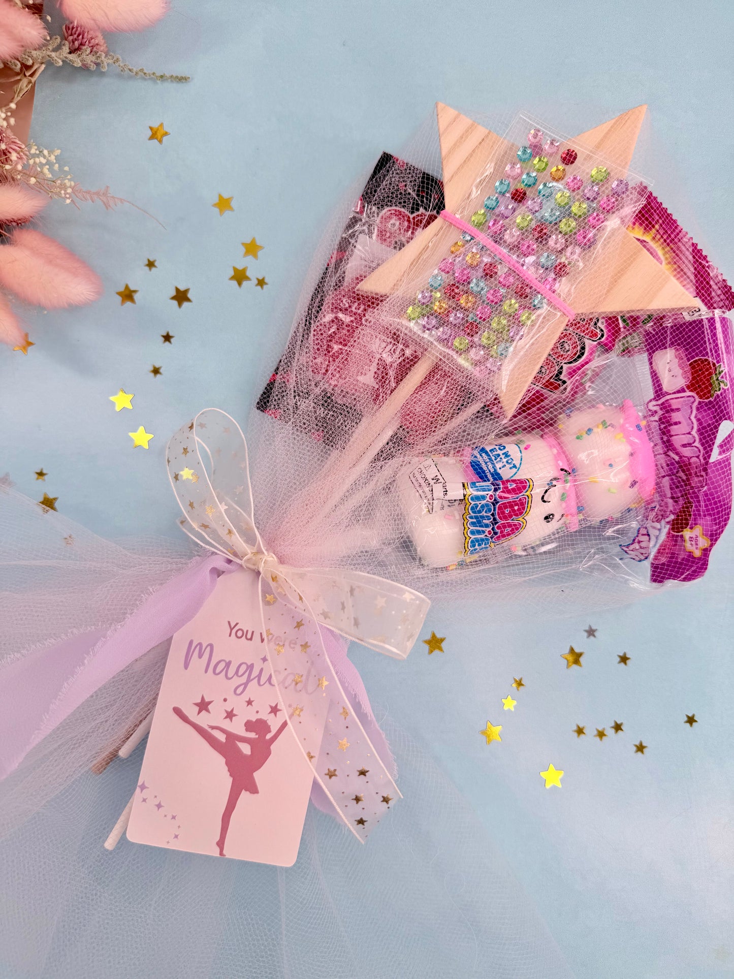 Gift with pink ribbon and tag on a light blue background with star confetti