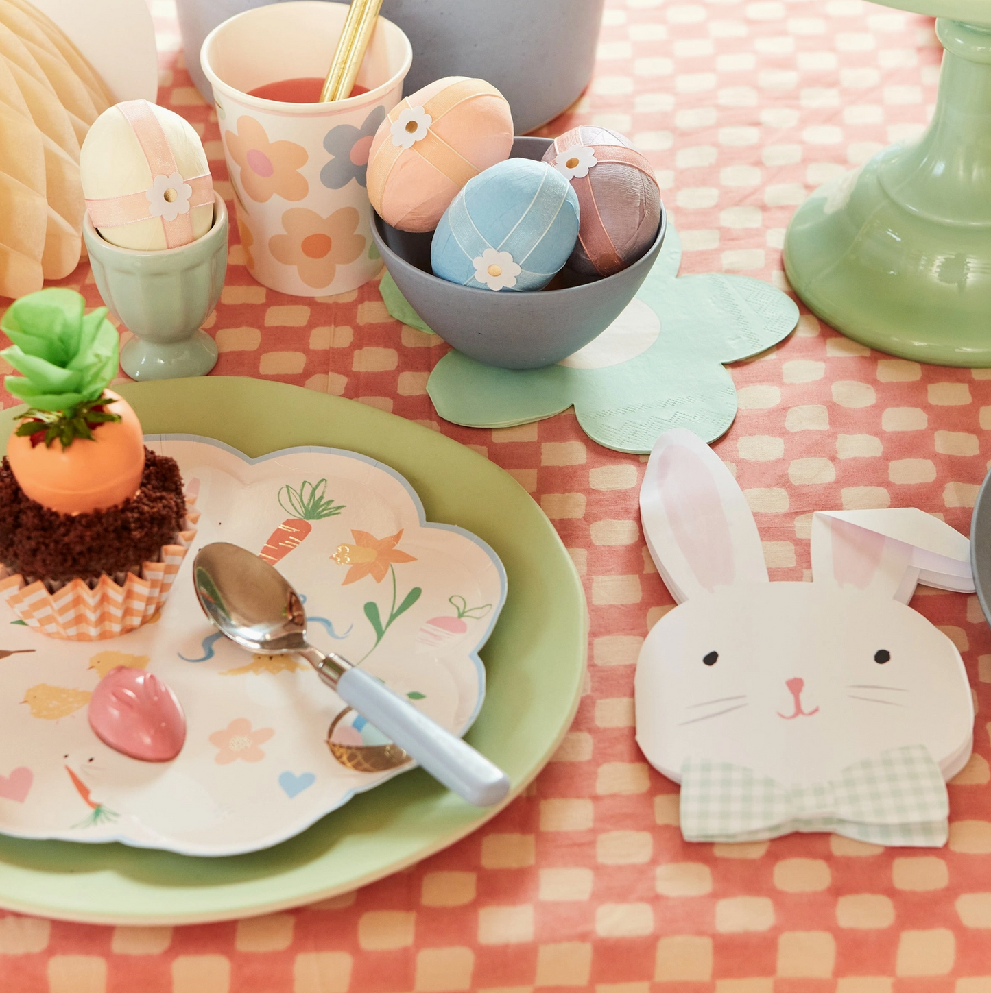 Easter-themed table setting with bunny decorations, colorful eggs, and a checkered tablecloth.