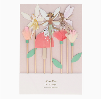 Set of fairy cake toppers with flowers on sticks against a light pink background