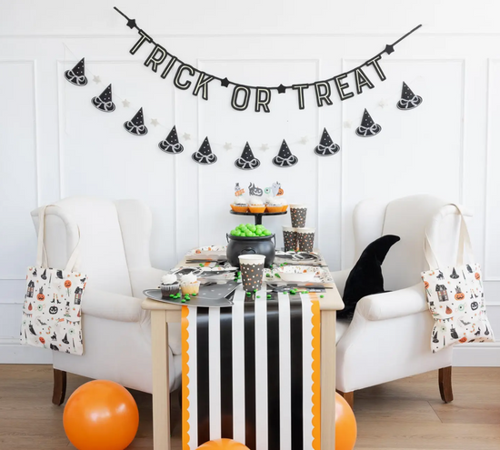 Halloween-themed room with 'Trick or Treat' banner, table decorations, and chairs.