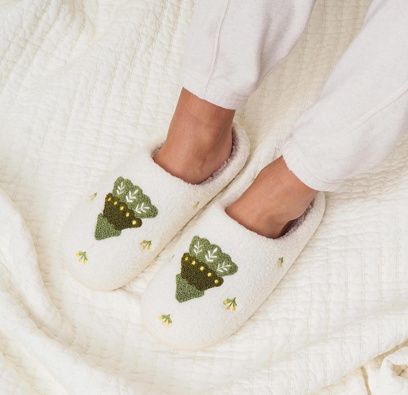 White slippers with green tree designs on a white background