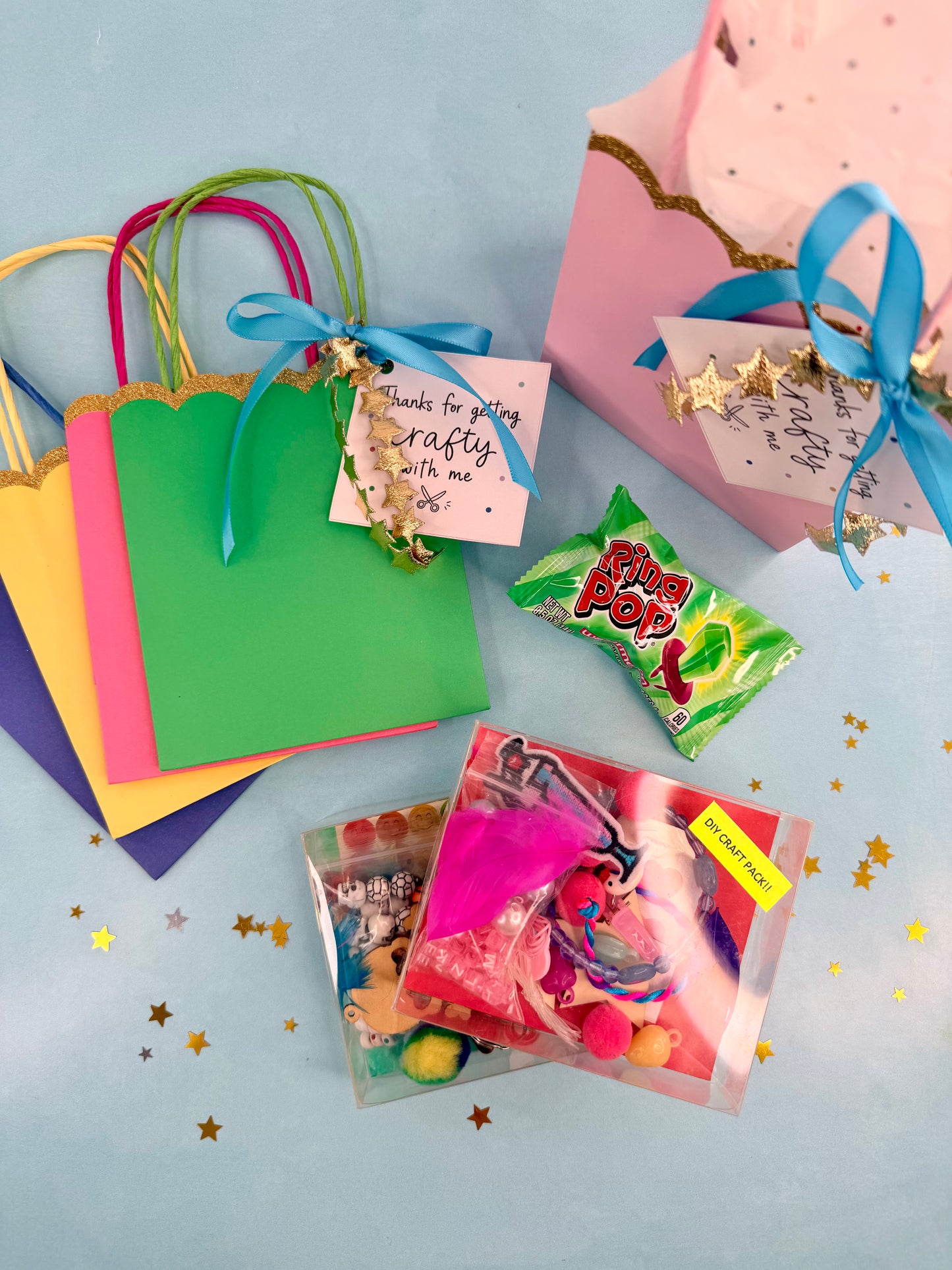 Colorful gift bags with ribbons, candy, and small packages on a light blue background.