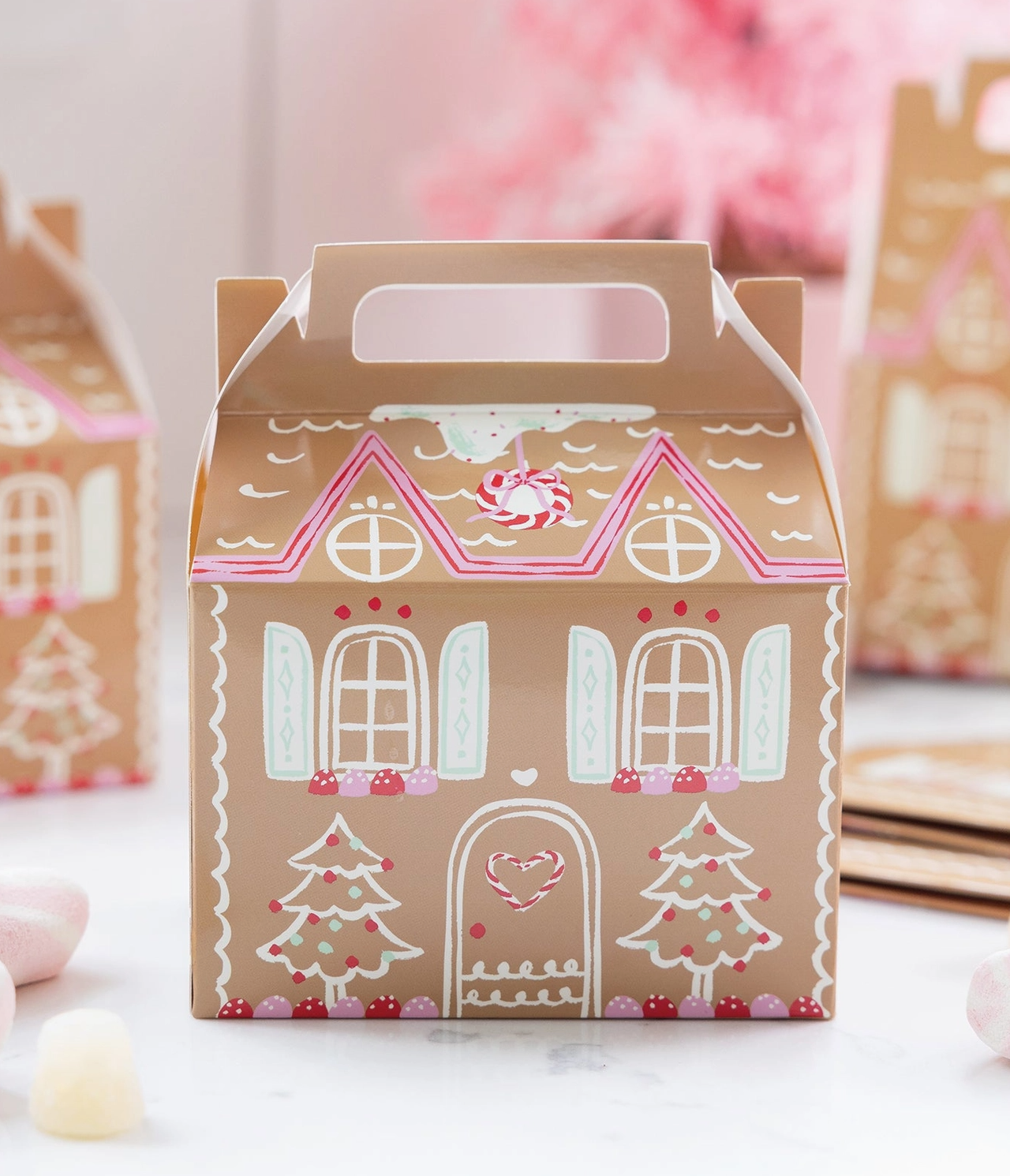 Gingerbread house-shaped gift box with decorative elements on a light background