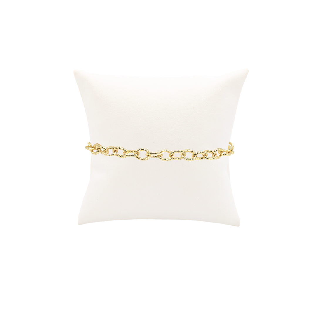 Gold chain belt on a white cushion with a white background