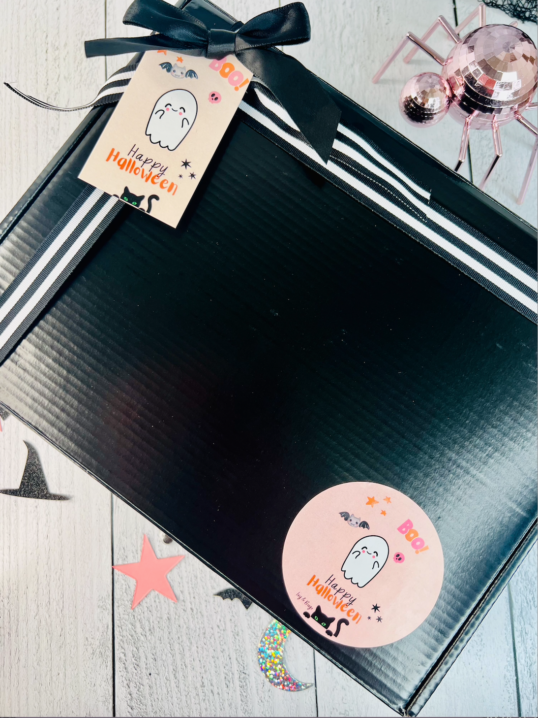 Black gift box with a 'Happy Halloween' tag and sticker on a wooden surface.