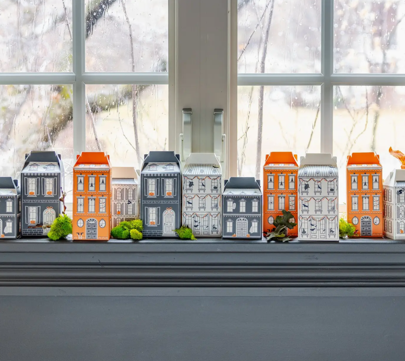 Model houses on a windowsill with a snowy outdoor view