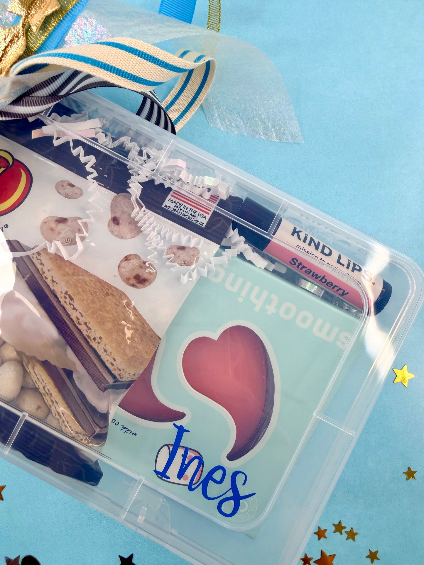 Clear plastic container with snacks and a heart-shaped name tag on a blue background