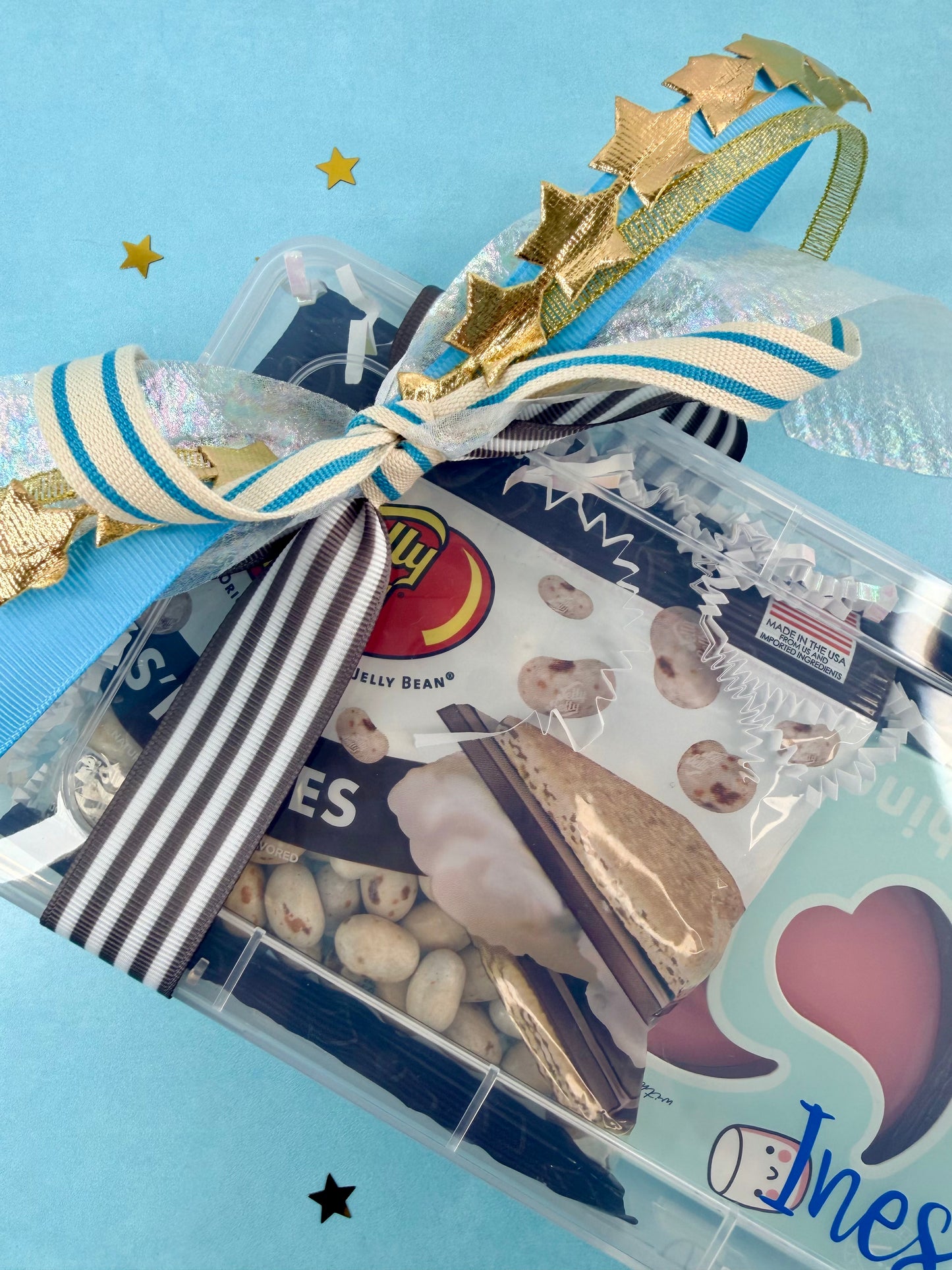 Party favor bag with gold tiara, star decorations, and candy on a blue background