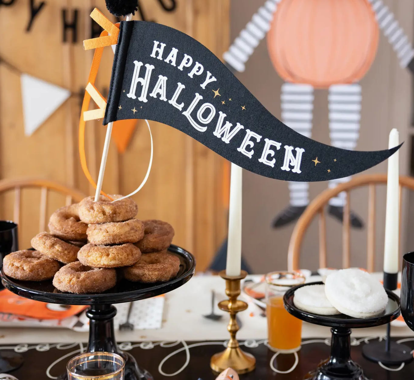 Halloween-themed table setting with 'Happy Halloween' banner, donuts, and candles.