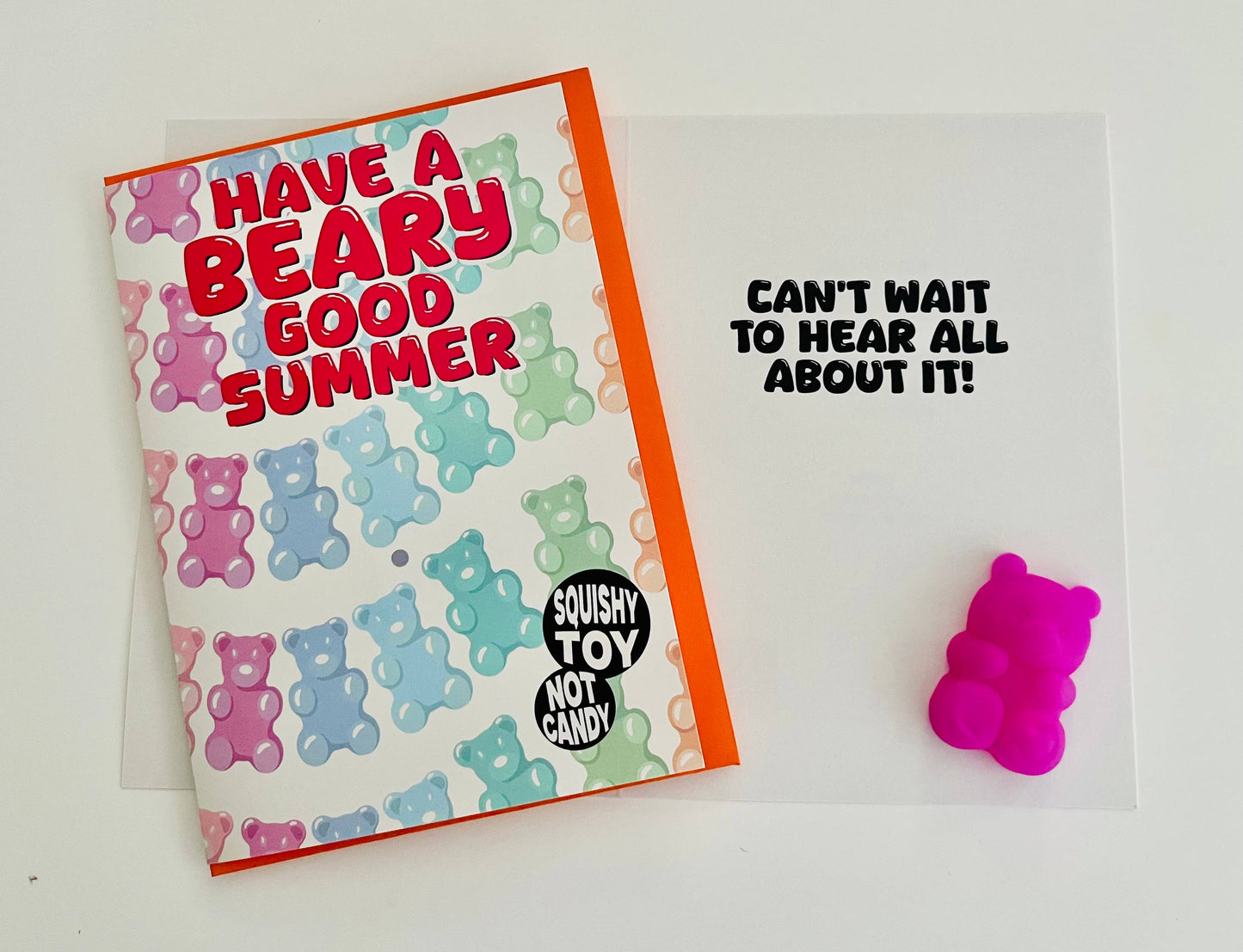 Card with colorful bear pattern and text, next to a pink gummy bear toy on a white background