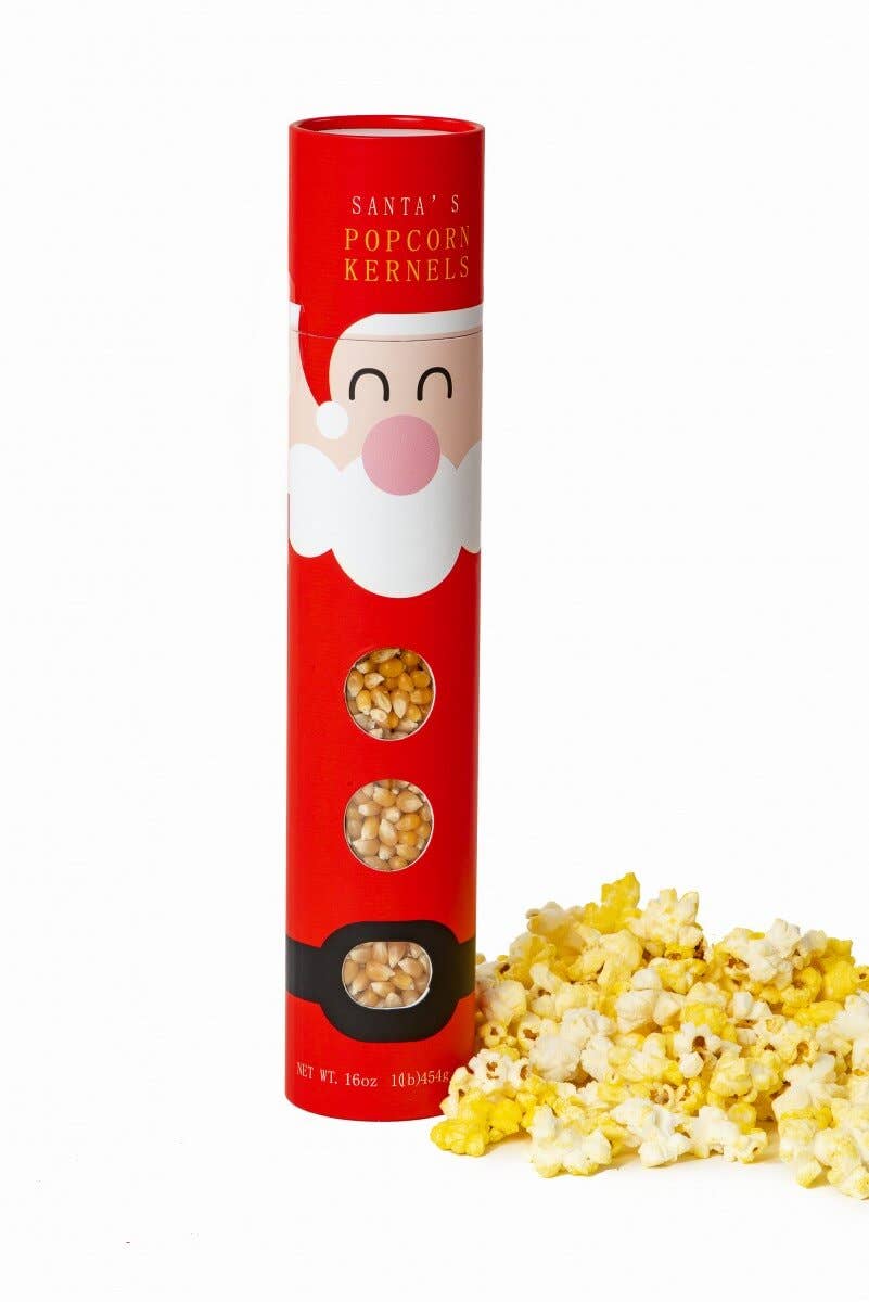 A red cylindrical tube labeled 'Santa's Popcorn Kernels' with a Santa face graphic and windows showing unpopped kernels, next to a pile of popped yellow-and-white popcorn on a white background.