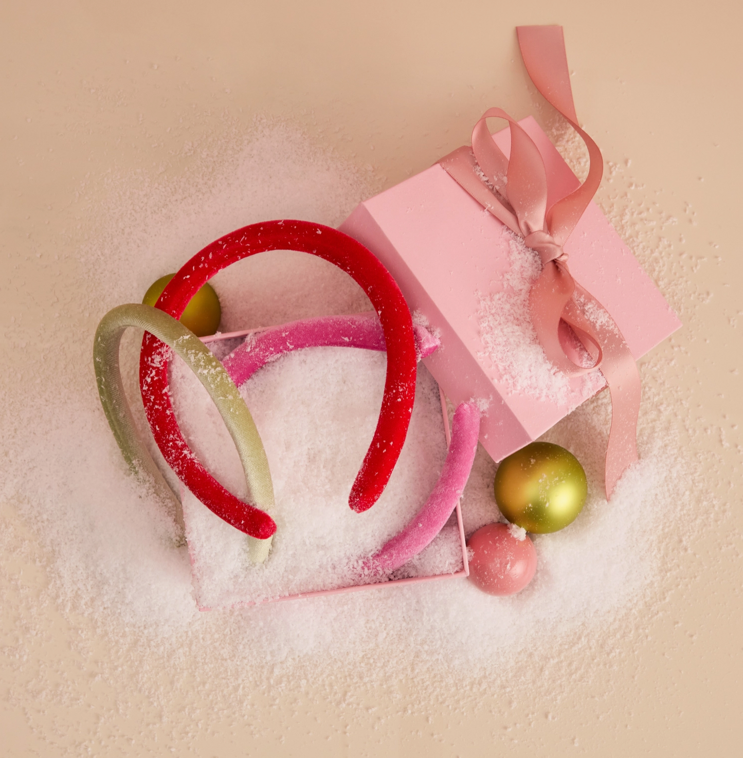 Colorful hairbands and a pink gift box with a bow on a textured beige background