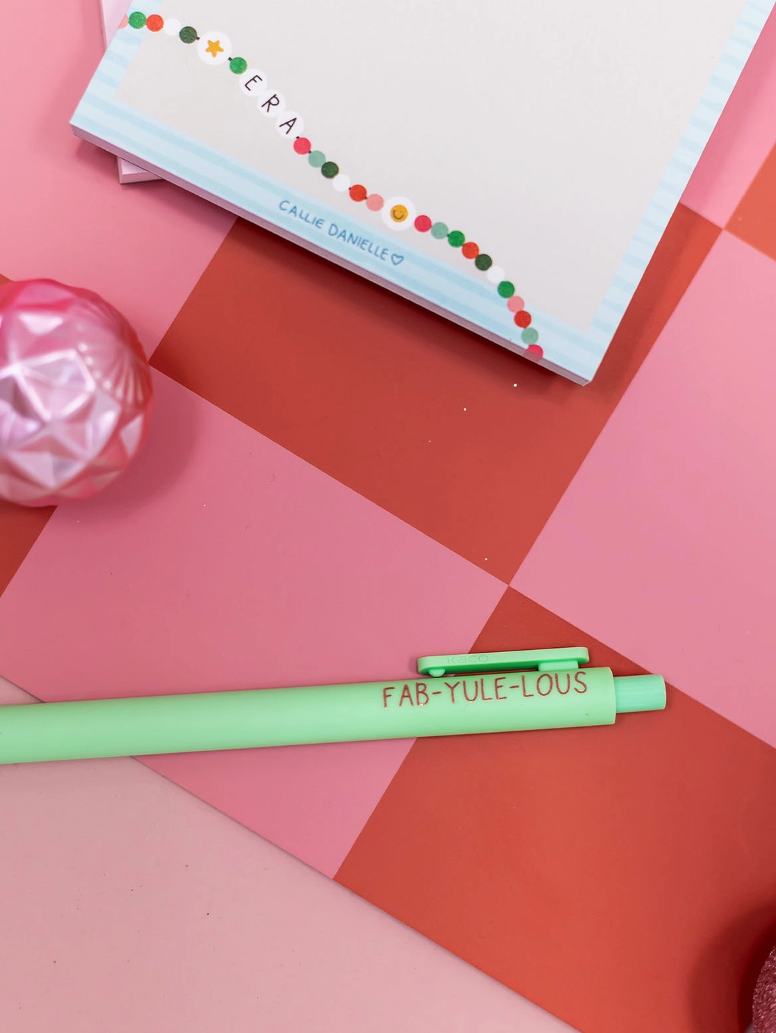 Green pen with 'FAB-YULE-IOUS' text on a pink and orange geometric background