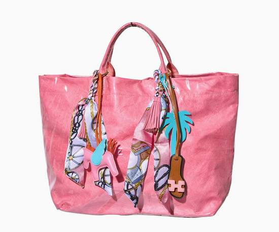 Pink tote bag with decorative keychains on a white background