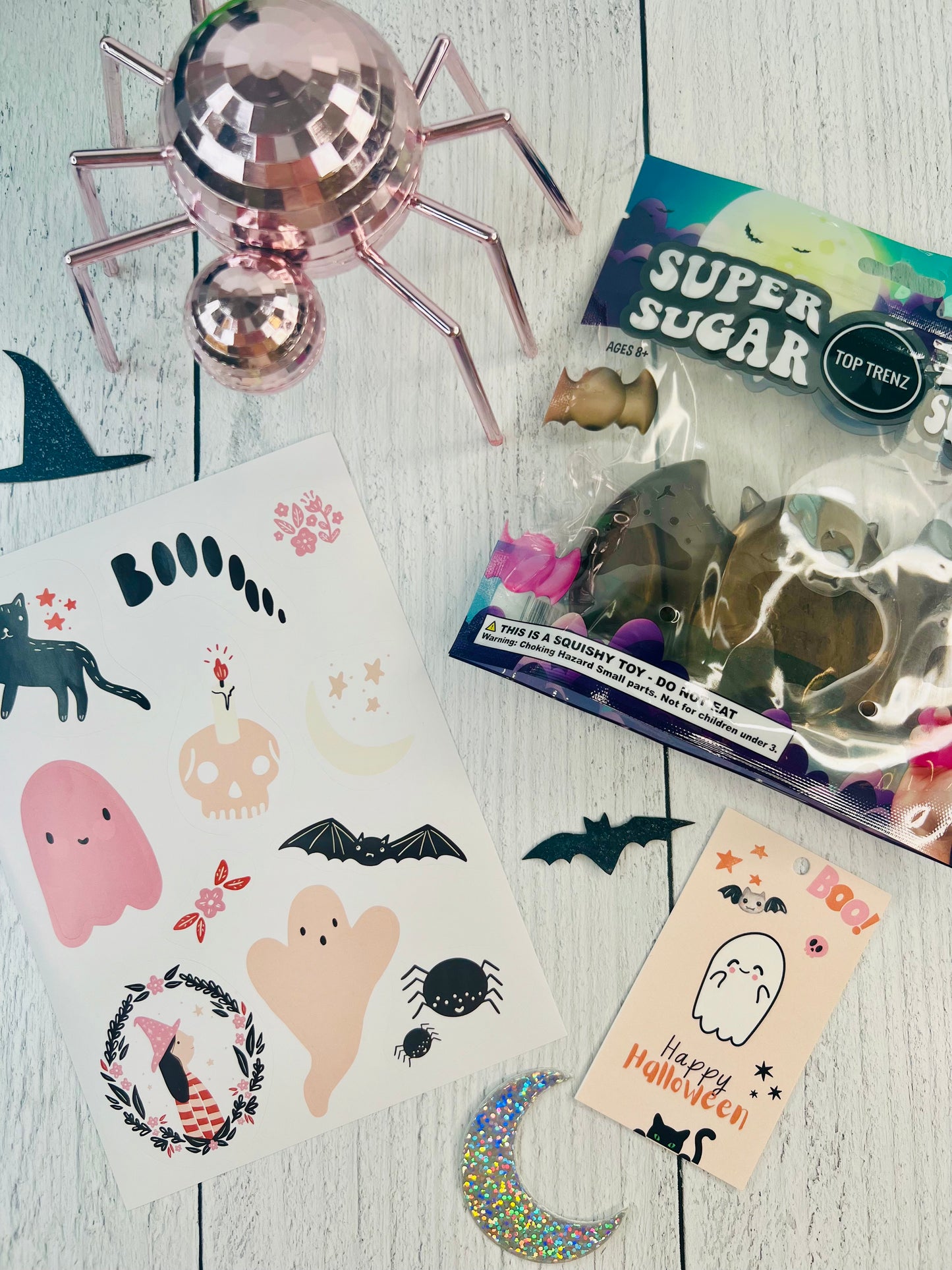Halloween-themed items including stickers, a toy, and a card on a wooden surface.