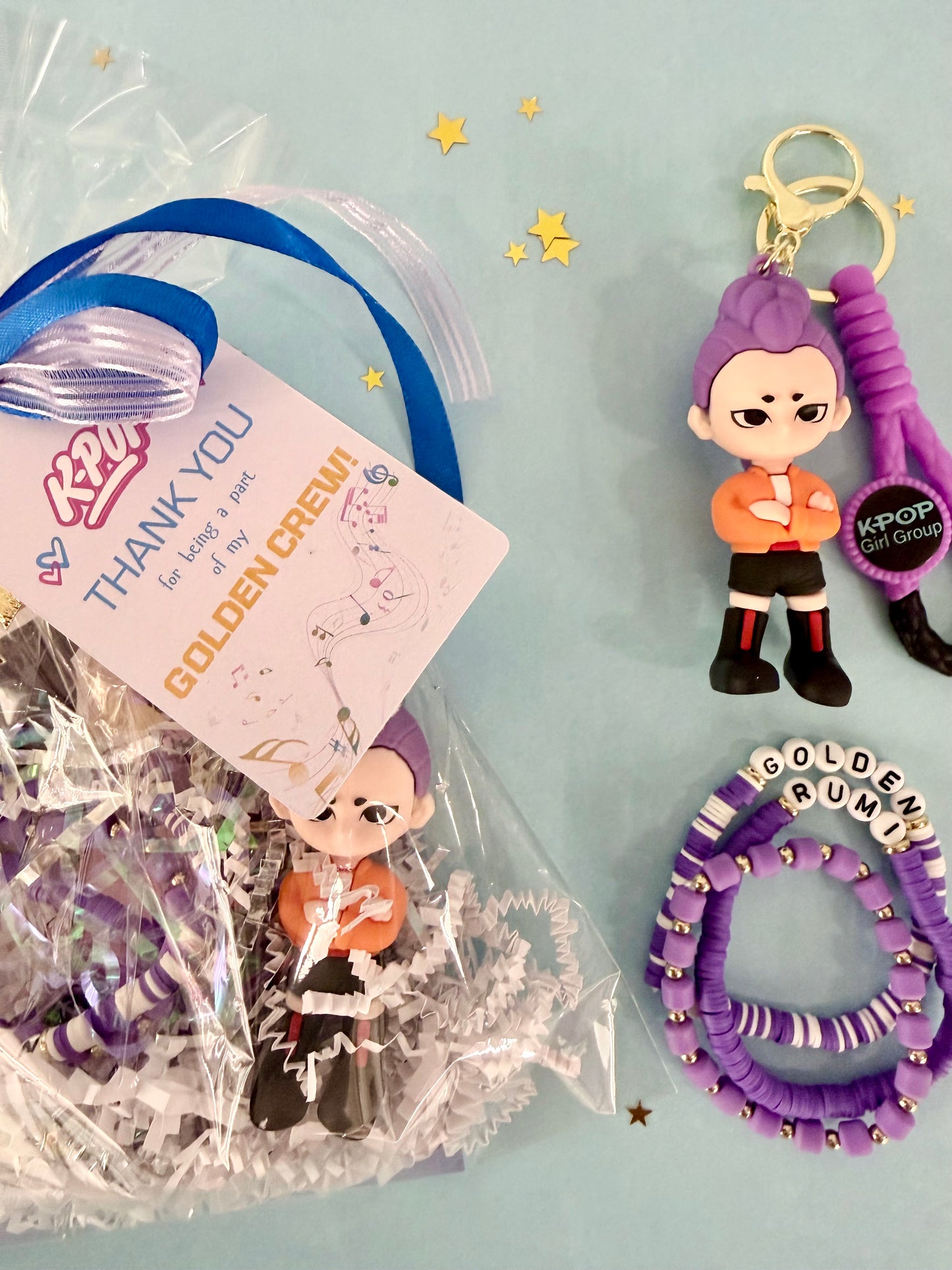 KPOP fan gift set with figurine, hair tie, and keychain on a light blue background