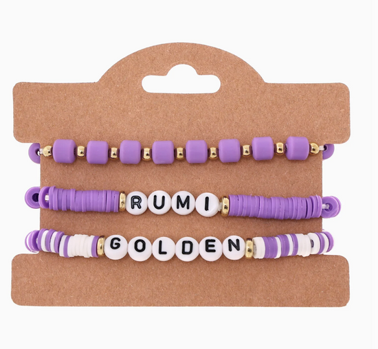 Set of purple and gold beaded bracelets on a cardboard display card.