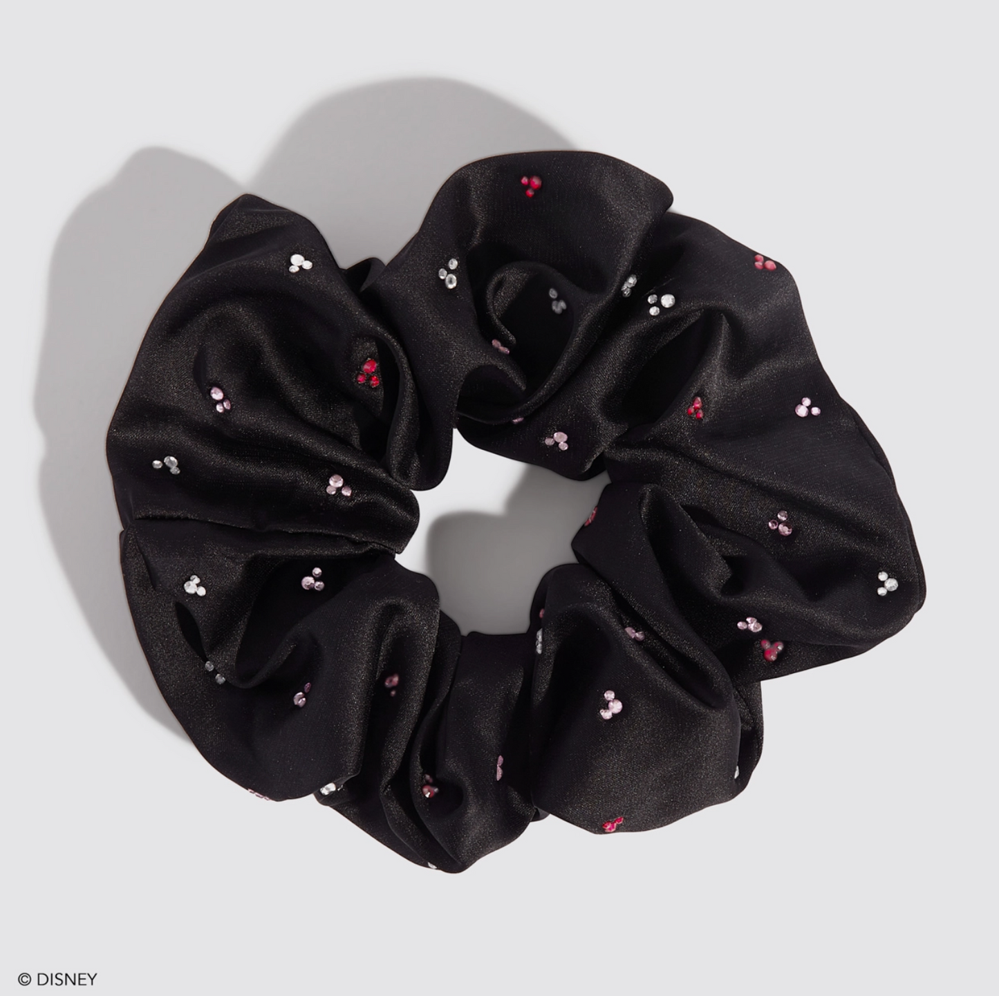 Black scrunchie with small red and white details on a light gray background