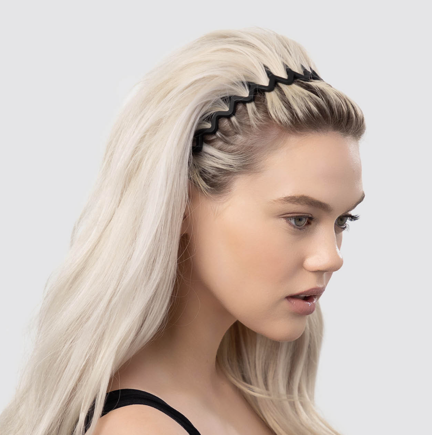 Woman with blonde hair wearing a black headband against a light gray background