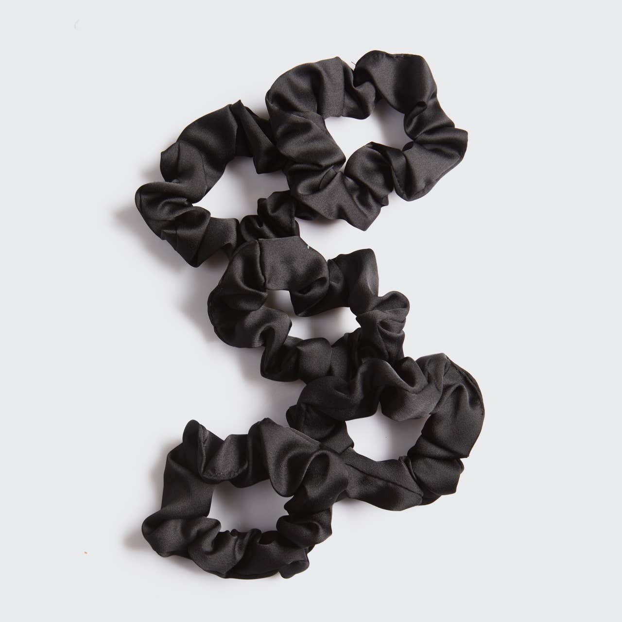 Set of black scrunchies on a light gray background