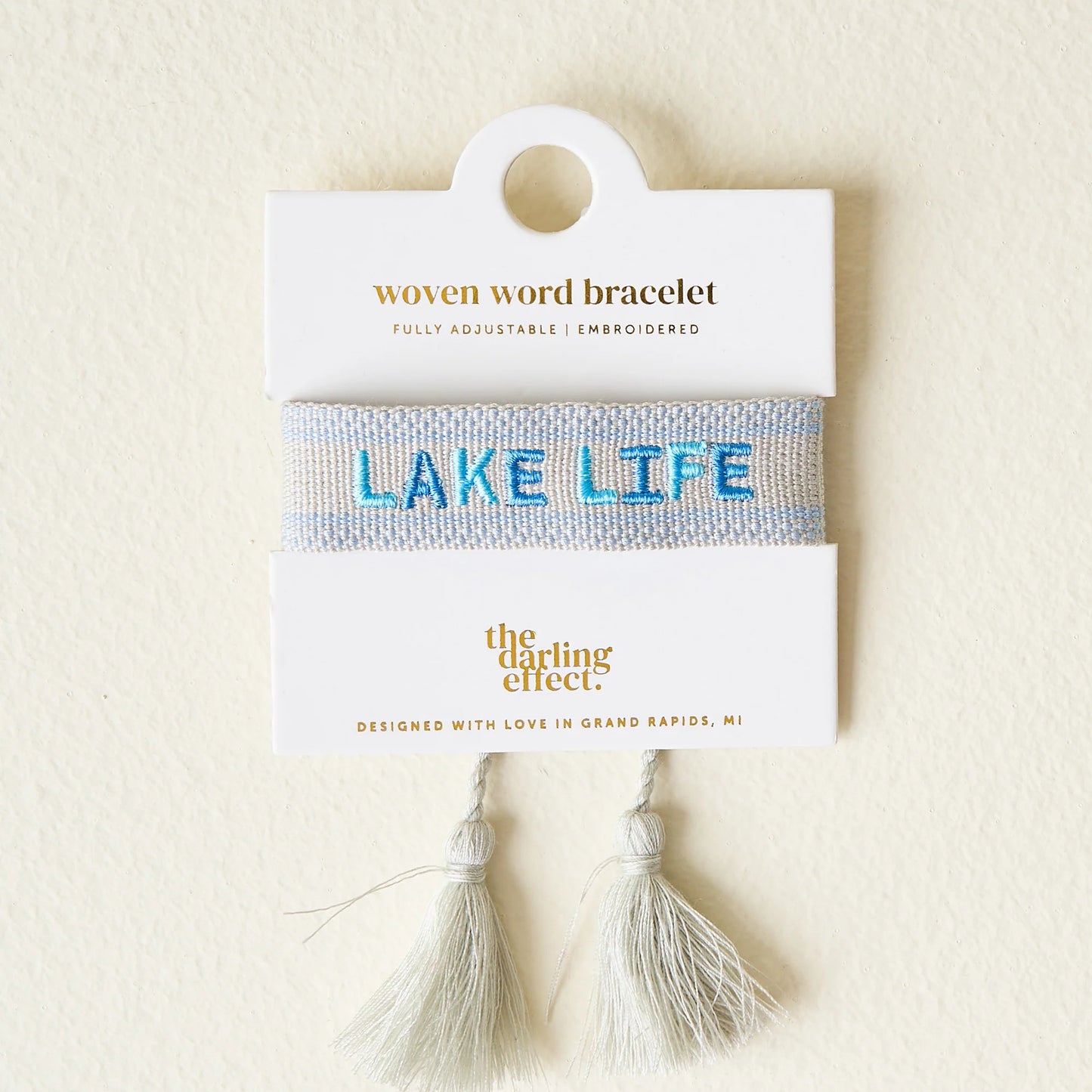 Woven word bracelet packaging with 'Lake Life' text on a beige background