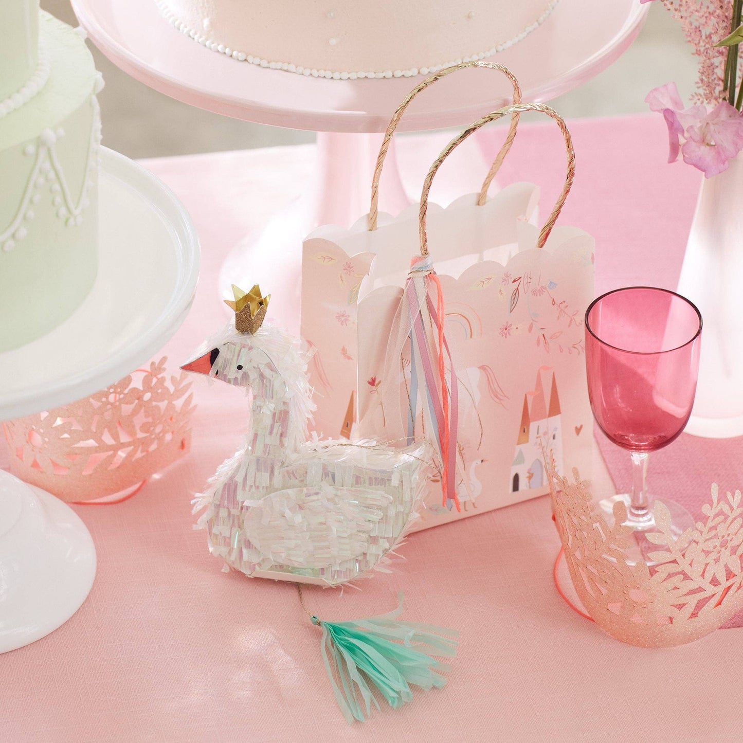 Decorative swan basket with a pink background featuring a cake and glass.