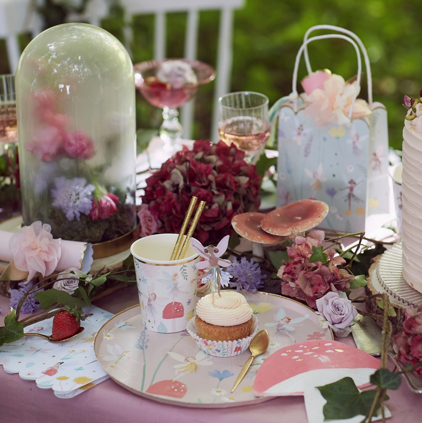 Decorative table setting with flowers, a cupcake, and fairy-themed elements.