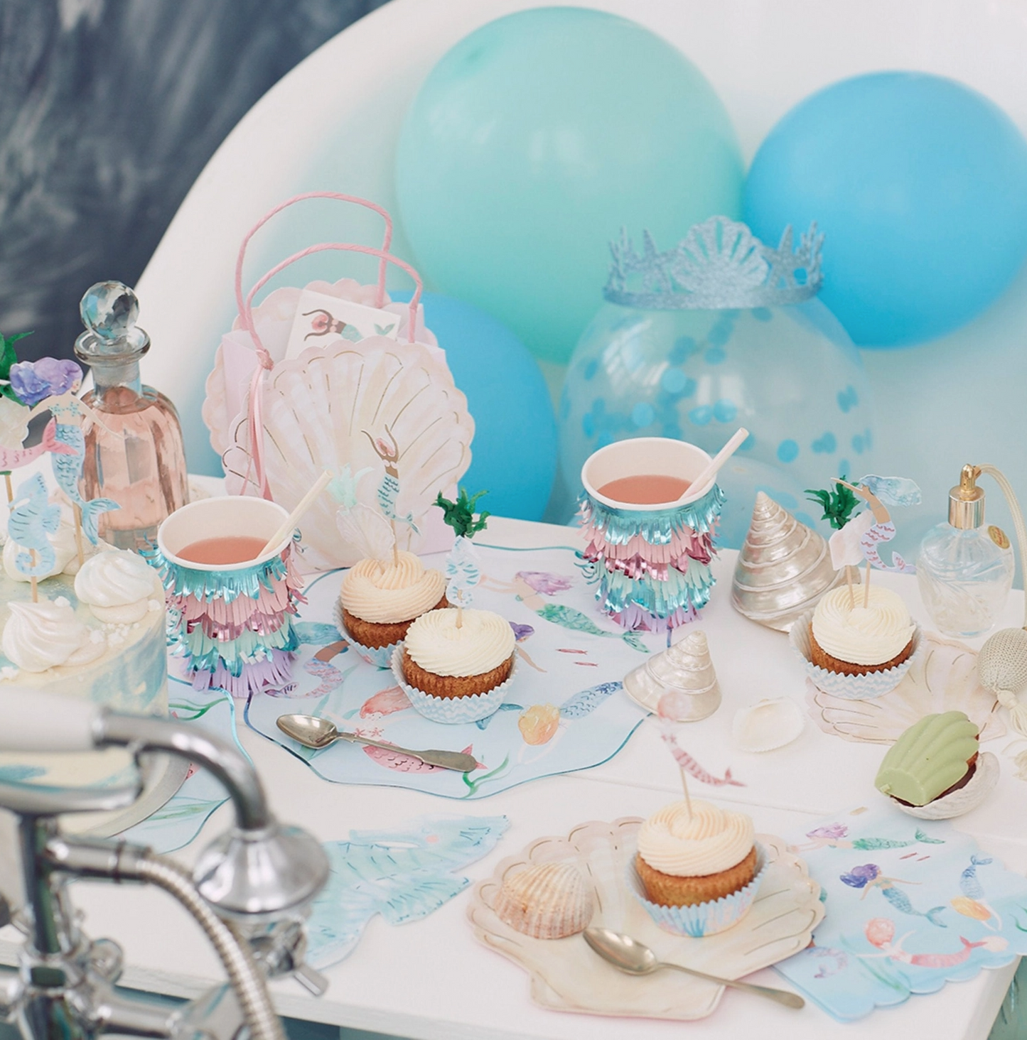 Children's birthday party setup with balloons, cupcakes, and decorative items on a table.
