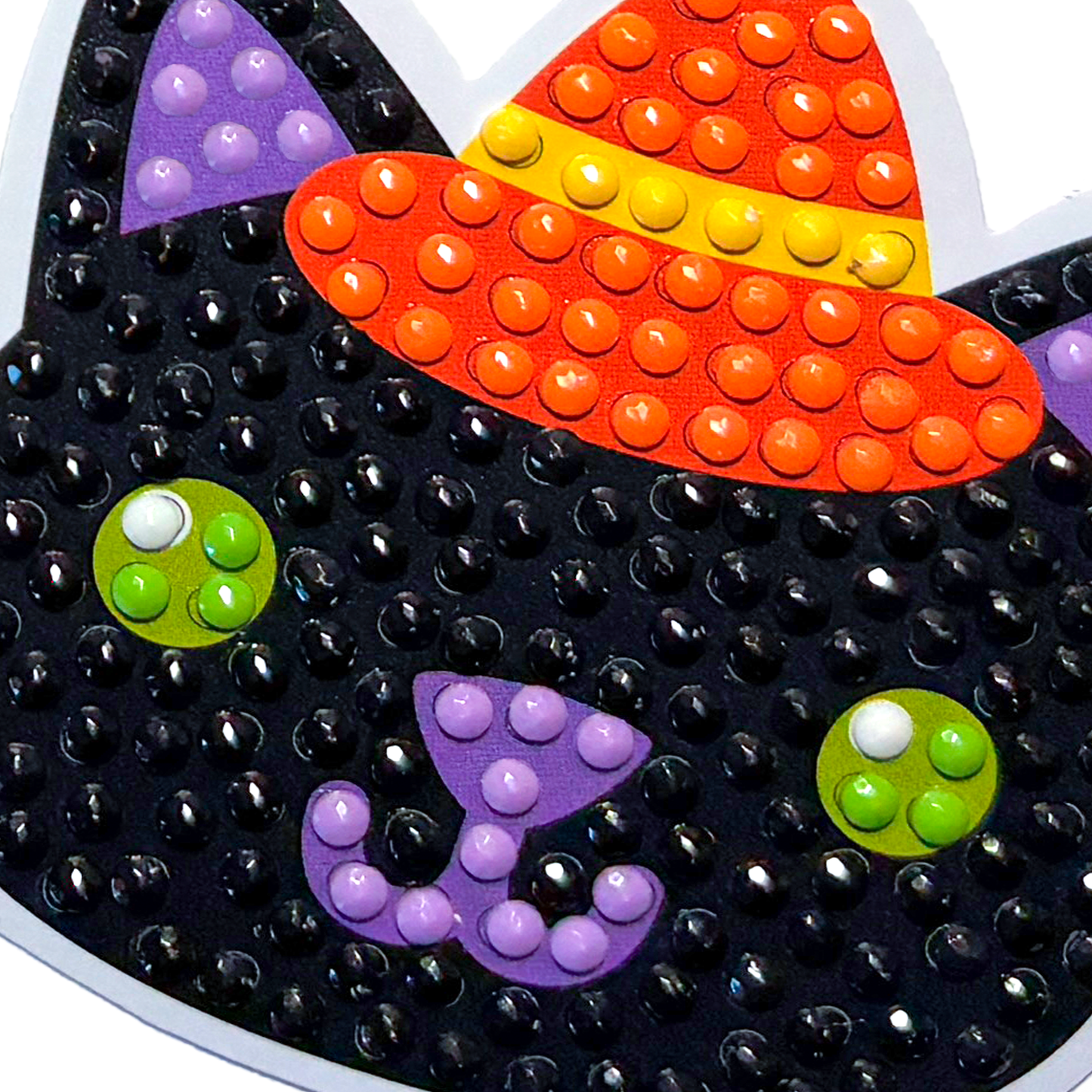 Halloween-themed decorative item with black cat face, orange candy corn hat, and colorful buttons.