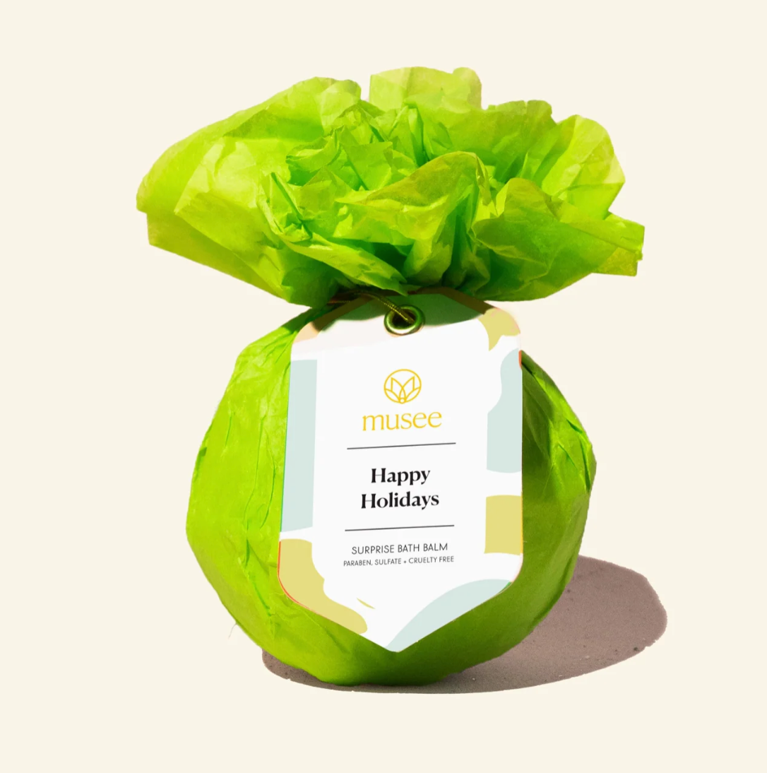Green bath balm wrapped in tissue paper with a 'musee' label on a beige background