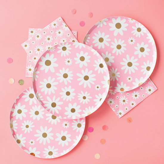 Set of paper plates and napkins with daisy pattern on a pink background