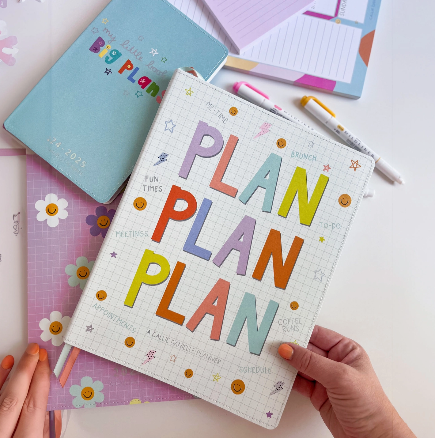 A colorful planner titled 'PLAN PLANNER' with a cartoonish design, featuring a variety of illustrations such as stars, planets, and flowers, and a vegan leather cover.
