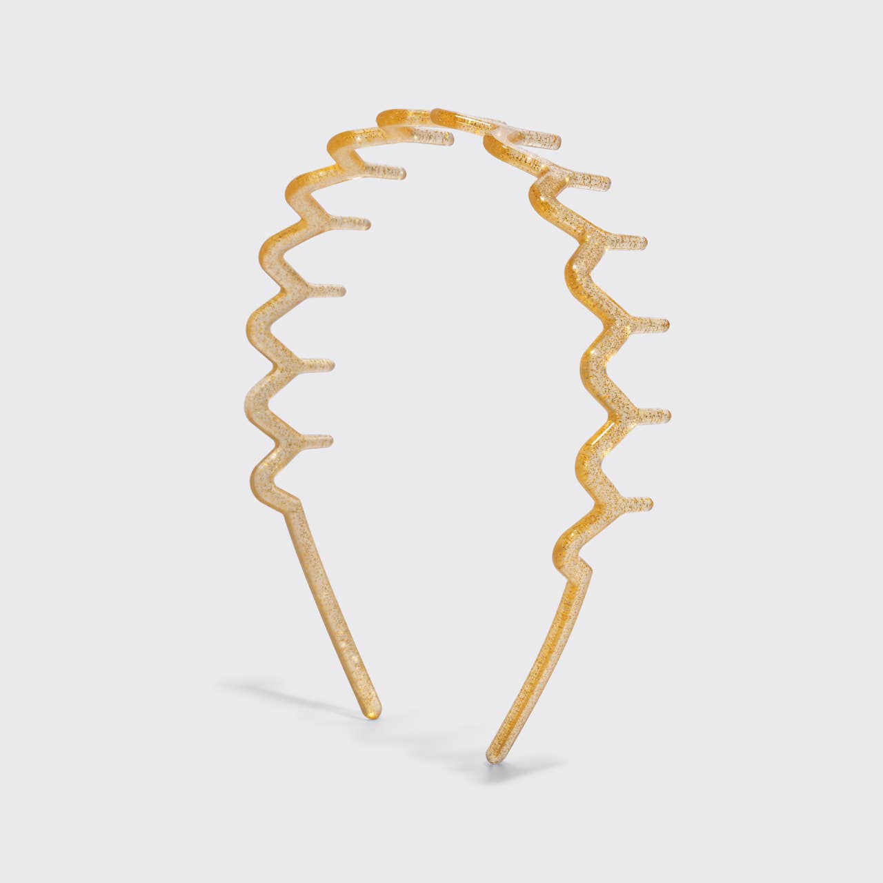 A gold glittery wavy headband with a zigzag pattern, displayed on a light gray background.
