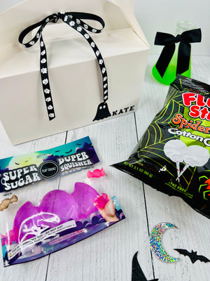Halloween-themed products including a bag of cotton candy, candy, and decorative items on a white surface.