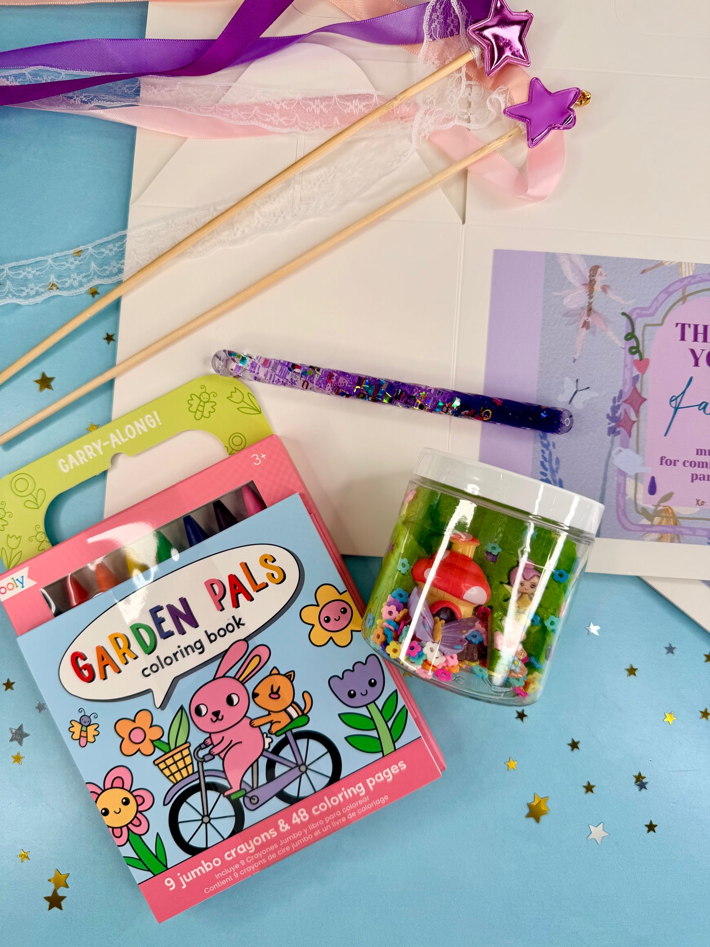 Coloring book, crayons, and other stationery items on a blue surface with stars.